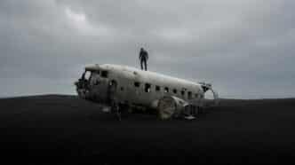 person standing on wrecked airplane under gloomy sky